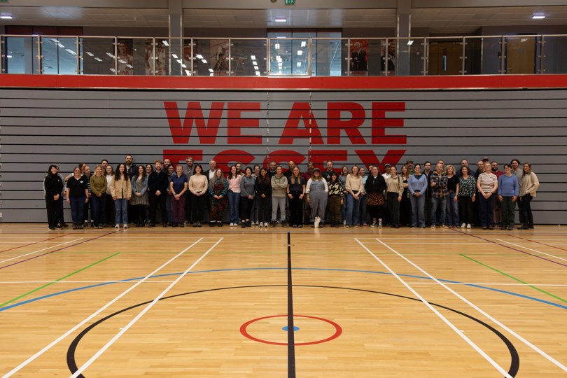 A group photo of Place Services staff members standing in front of the We Are Essex sign.